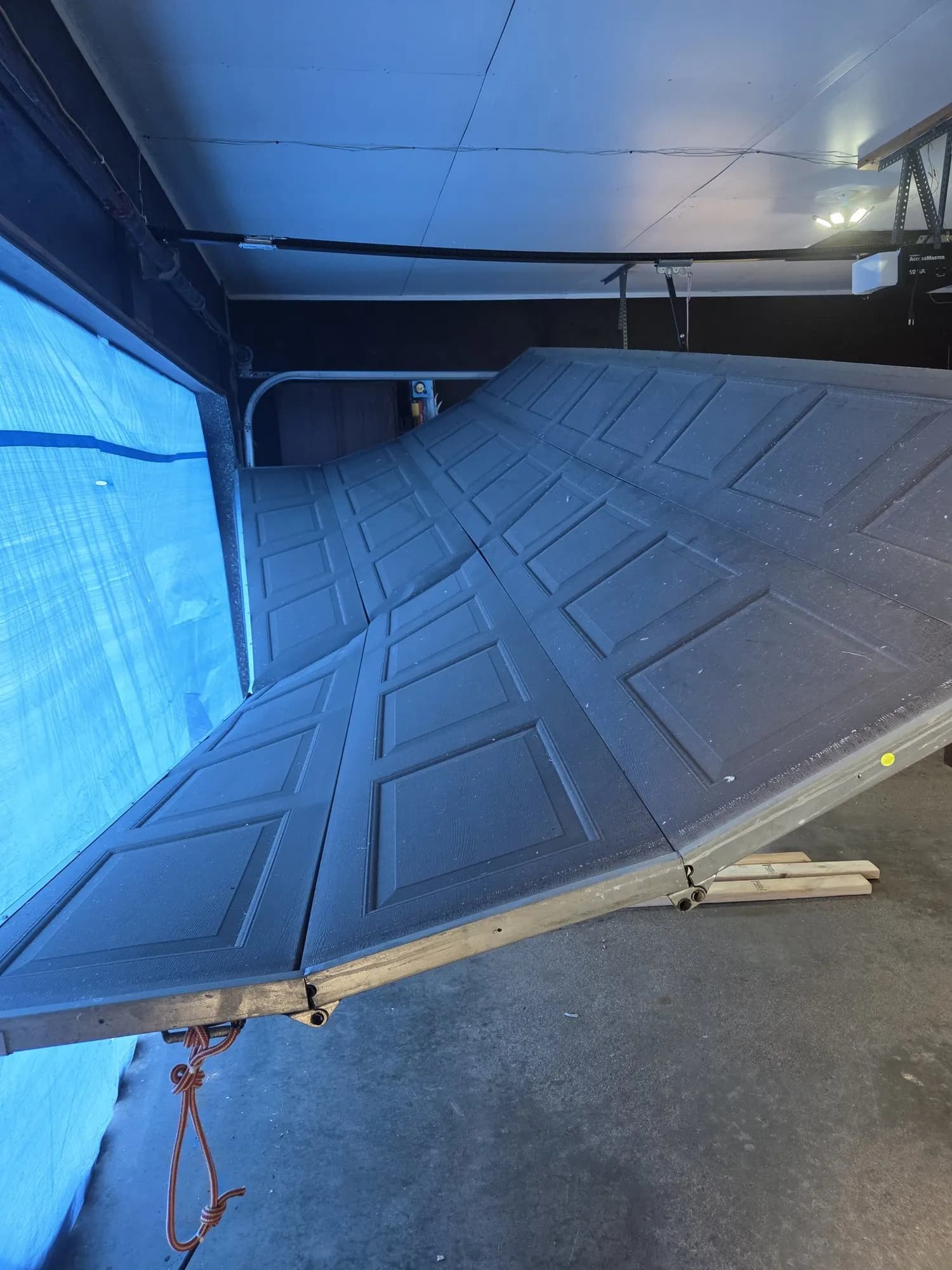 Storm-damaged metal garage door, an example of contents-and-structure loss Shield restores.