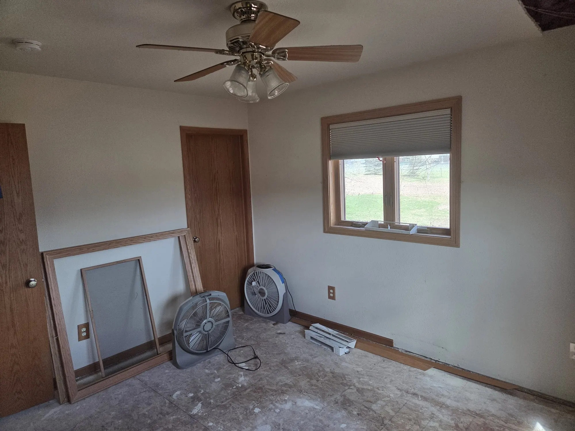 Air movers running in a stripped room during a water-damage dry-down.